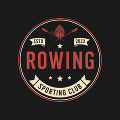 Circular vintage logo design featuring a rowing boat, oars, and text, on a dark background.