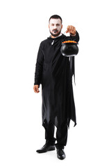 Young man dressed as vampire for Halloween with cauldron of candy corns on white background
