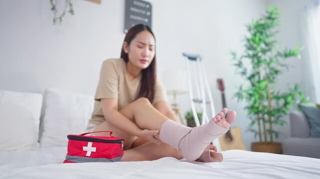 Injured Asian young woman wearing splint on leg in cozy bedroom at home
