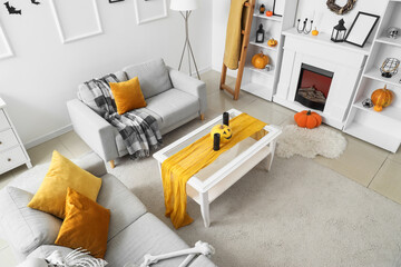Interior of light living room decorated for Halloween with sofas, table and fireplace, top view