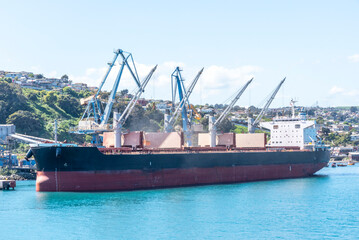 Naklejka premium San Antonio, Chile - bulk carrier ship moored in the port terminal, loading operation in progress. 