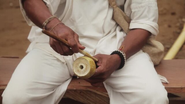 Close-up of the hands of an Aruhaco man holding a poporo and chewing coca leaves.