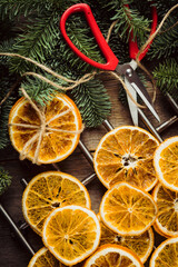 Making of christmas aroma garland with dried oranges. Dried oranges with fir branches on the rustic wooden background. Christmas mood. Shot from above.