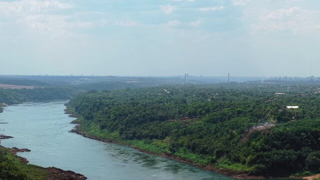Triple Frontier&mdash;where Argentina, Paraguay, and Brazil converge at the Paran&aacute; and Iguaz&uacute; Rivers, blending forest canopy, urban edges, and cross-border geography, drone panning reveal shot