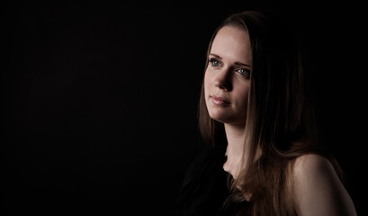 Naklejka premium Studio portrait of young woman looking away on black background