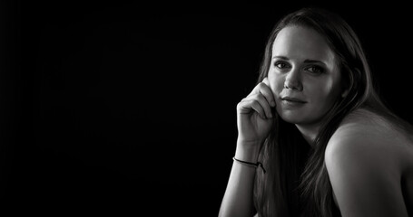 Young woman with hand on face posing for a black and white portrait in a professional studio