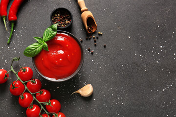 Bowl of tasty tomato sauce and different spices on black background