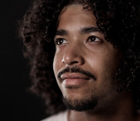 Close up portrait of a young thoughtful african american man with afro hair and goatee looking up...