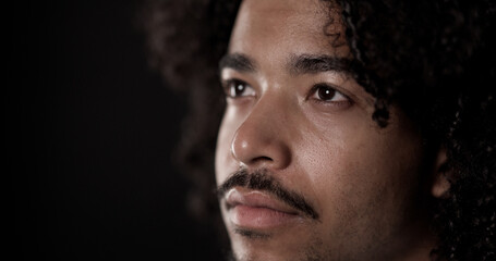 Obraz premium Portrait of a young thoughtful african american male model posing in studio against a dark background, looking away from camera