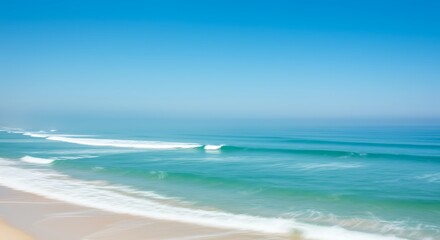 Ocean waves rolling onto sandy beach under a clear blue sky