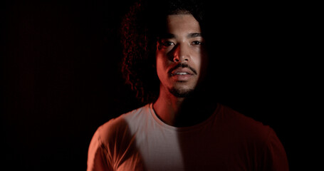 Dramatic portrait of a young african american model posing in a studio, illuminated by a red light...