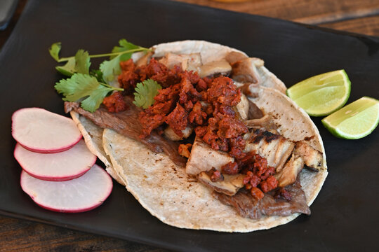 tacos mexicanos de carne y chorizo acompa&ntilde;ada de r&aacute;banos y lim&oacute;n