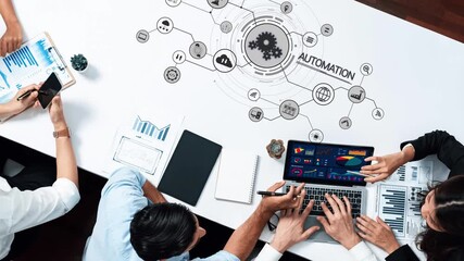 A diverse team collaborates at a sleek office table, analyzing data visualizations on a laptop while engaging in automation concepts for business innovation. Raster - Powered by Adobe