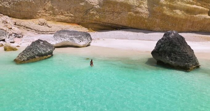 Woman On A Pristine White-sand Beach With Turquoise Water And Large Rock Formations In Socotra Island, Yemen. - aerial shot