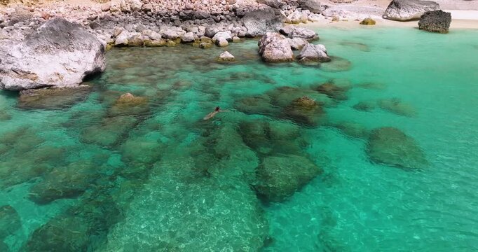 Woman In Bikini Swimming In The Clear, Turquoise Water Of Shoab Coast In Socotra Island, Yemen. - aerial shot