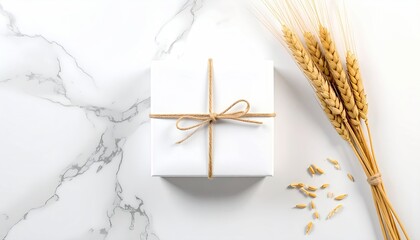 A white wrapped present tied with twine, on marble with wheat stalks and grains
