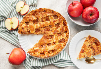 Homemade apple pie with a slice and fresh apples