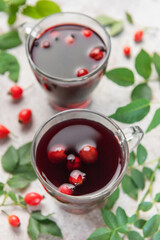 Drinking hot rosehip tea with berries and leaves
