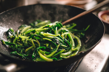 Chef cooking stir-fried vegetables in a hot wok with flames rising, creating a dramatic scene in a professional kitchen. Asian cuisine concept showing high heat, fresh ingredients, and motion.