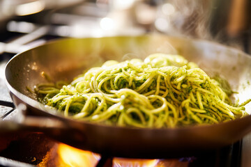 Close-up of spaghetti bolognese cooking in a pan on the stove, rich tomato meat sauce glistening in warm light, representing homemade Italian comfort food.