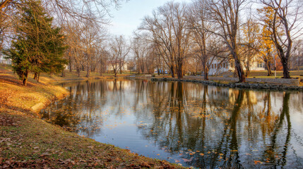 Obraz premium Serene autumn landscape featuring a tranquil pond surrounded by bare trees and fallen leaves, reflecting the peaceful atmosphere of nature in a quiet park setting