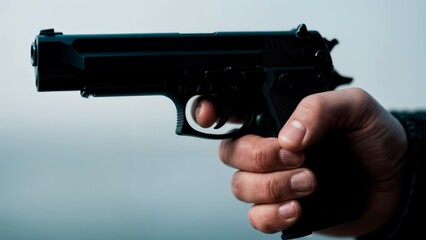 A close-up of a person's hand holding a gun. Gun crime, danger, violence, armed conflict, thriller.