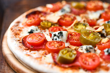 Pizza with salami, jalapeno pepper, cherry tomatoes and mozzarella cheese. Soft focus.	