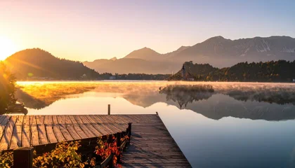 Keuken achterwand Reflectie Sunrise over a misty lake, dock in foreground, mountains reflected in calm water  © rega