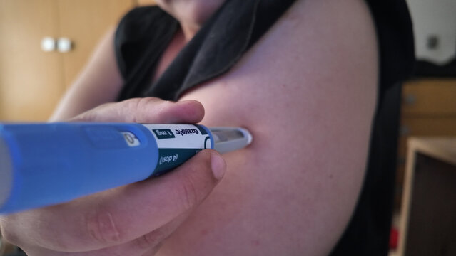 Ozempic Injection pen in use for subcutaneous medication. A close-up shot shows the device being administered to the upper arm, no brand names.