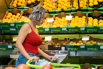 Young woman shopping fresh fruits in supermarket produce aisle