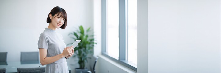 Young woman holding potted plant standing near window in modern minimalist home