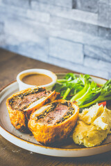 Beef Wellington Beef tenderloin topped with onion, mushroom, herbs, wrapped in turkey ham and wrapped in buttery puff pastry