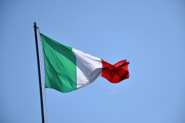 Waving flag of Italy against blue sky