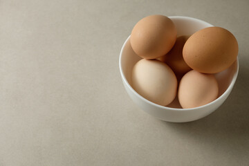 Freshly gathered eggs in a simple bowl on a soft background