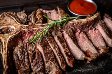 Sliced T-bone steak with rosemary and sauce closeup