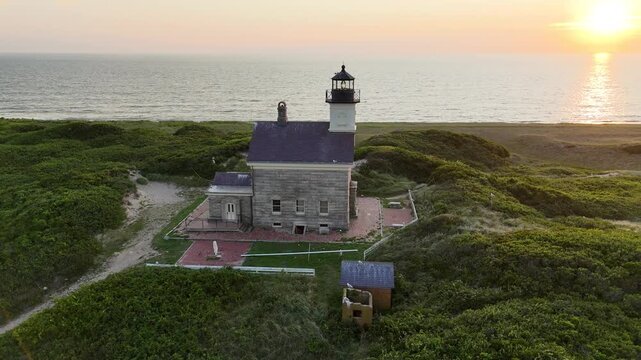 Aerial view of the North Light lighthouse standing proudly on Block Island amidst vibrant green foliage, against the backdrop of the ocean, New Shoreham, Rhode Island, United States.
