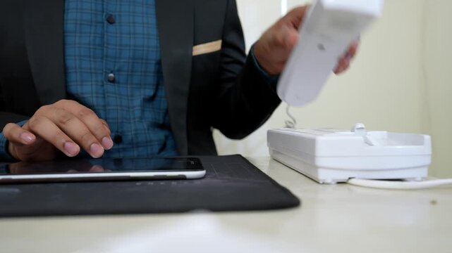 Person in a suit typing on a tablet, with a stapler nearby on a desk