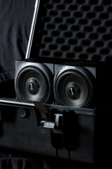 Two black audio speakers placed in an open protective case with foam padding, symbolizing safe transport of sound equipment. Photo