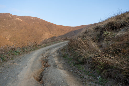 Winding dirt road in barren mountain landscape with snow traces