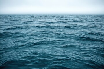 Fototapeta premium Rippled blue sea under a hazy, overcast sky.