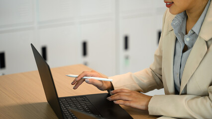 Hands of a businesswoman holding a stylus and working on a laptop computer