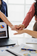 Business team joining hands showing unity and teamwork during meeting
