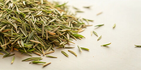 Fresh rosemary leaves are spread out on a light surface, showcasing their green color and fragrant texture, perfect for enhancing various dishes in a kitchen setting