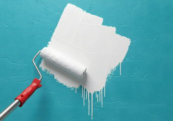 A paint roller with white paint is painting a blue wall, creating a textured surface and dripping effect, isolated on white background