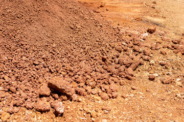 Excavation of red clay soil construction site material stockpile outdoor environment ground level view