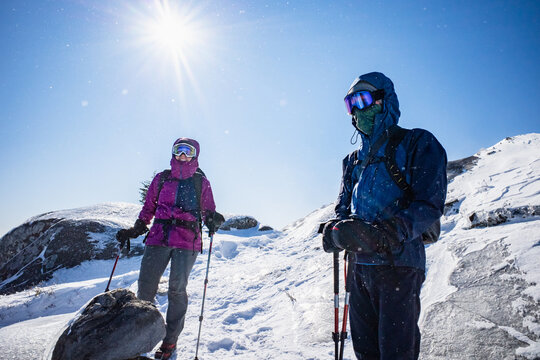 Hikers pause while descending a frozen mountaintop on a bluebird day