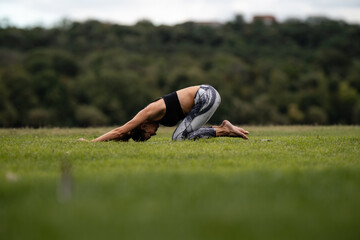 Woman performing child's pose yoga on green meadow