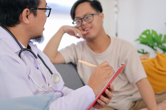 Therapist Consult an Asian Boy with Down Syndrome in the Living Room at Home