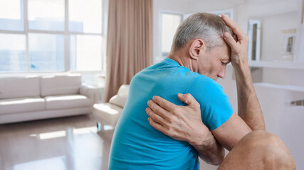 Upset tired young man feeling muscular pain after injury. Pain under the shoulder blade in man...