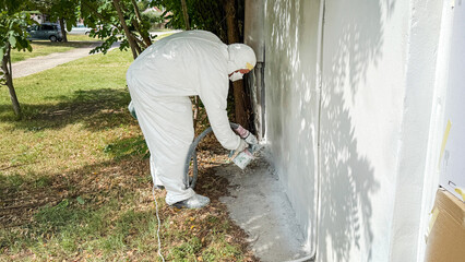 A technician in full protective gear sprays vibrant walls for Urban Renewal Day, evoking futuristic...